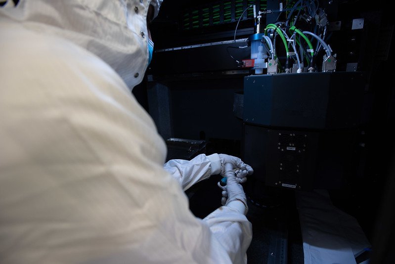 Studente di dottorato al lavoro con una stampante combinata getto di inchiostro aerosol jet, installata nella camera pulita di Polifab.