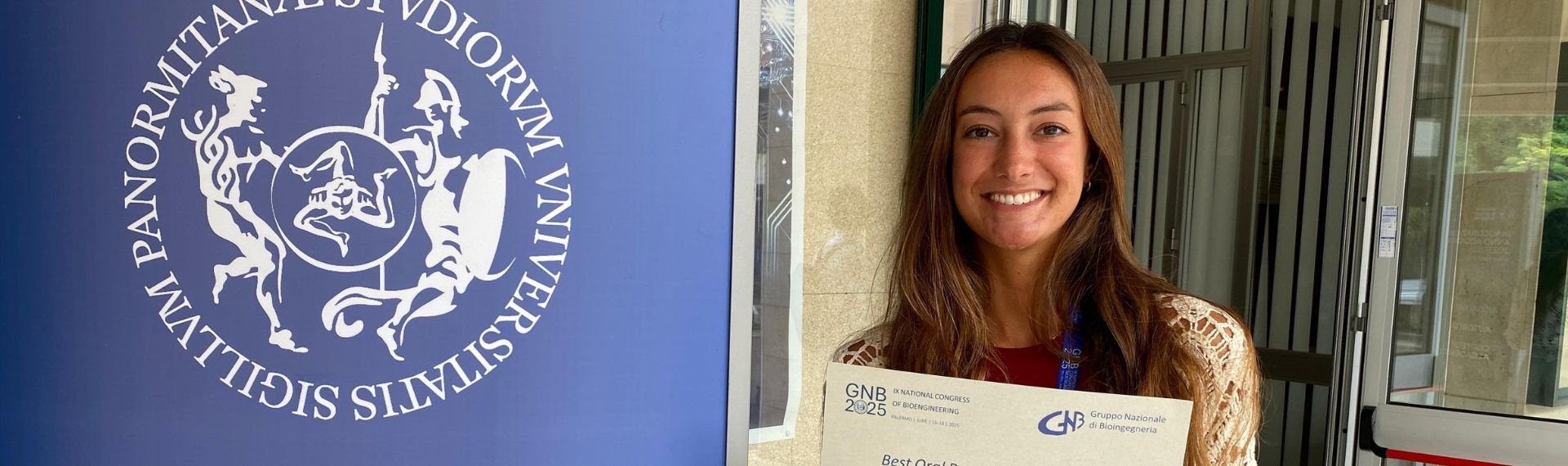 A woman is holding a certificate in front of an information board.