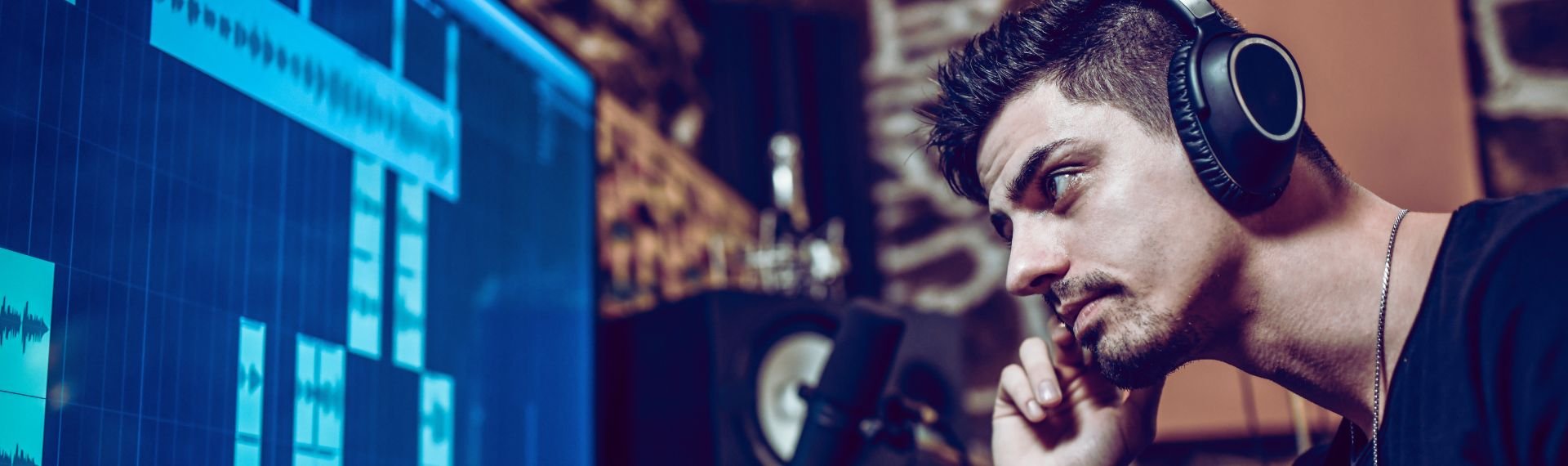 Man with headphones in front of a computer screen, focused on a digital task