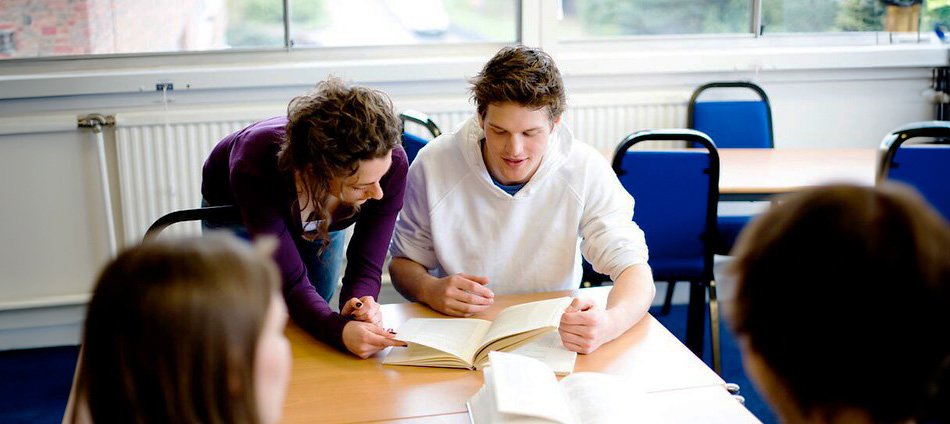 Due studenti che studiano insieme in un'aula, concentrati sui loro libri e appunti.