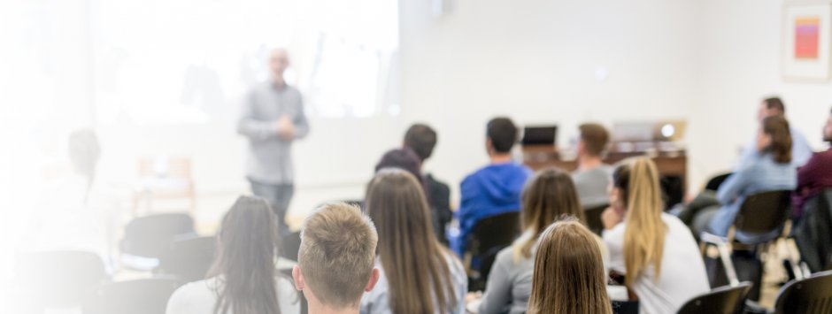 Un gruppo di persone sedute in aula, ascoltando attentamente l'insegnante.