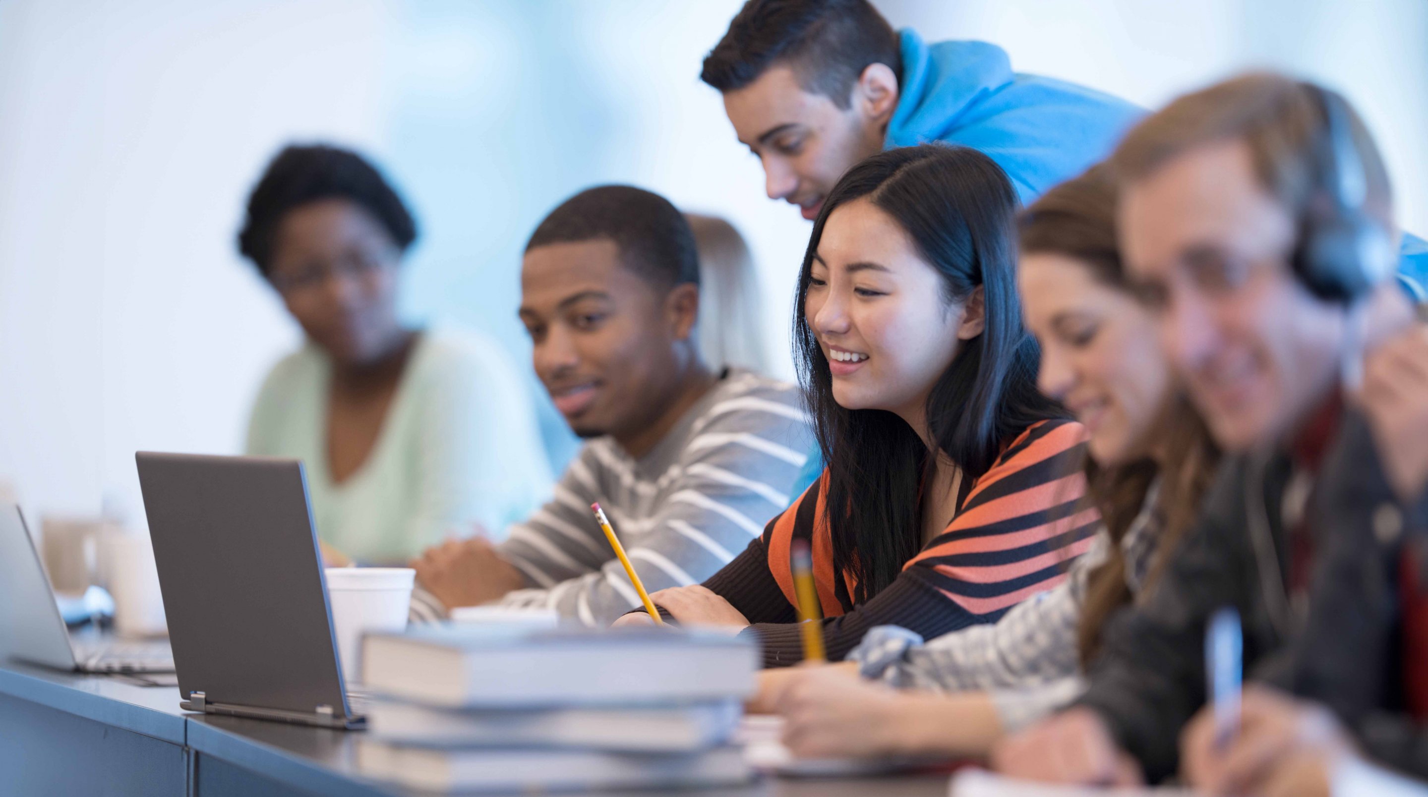 A group of young students sitting around a table, engaged in a lesson or workshop, with some smiling and interacting with each other.